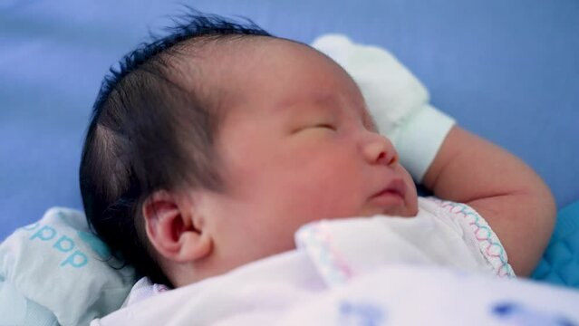 Infant boy asian newborn baby sleeping and peeping with his eye try to open close up shot