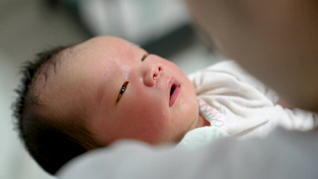 Newborn infant baby boy in asian mother arms sleeping happy