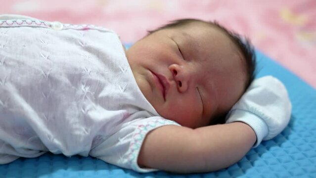 Asian newborn baby infant boy sleeping and smiling with his hands up