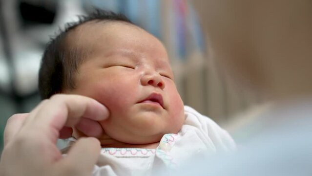 Infant baby boy in asian mother arms smiling and laughing newborn