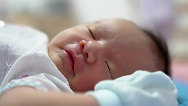 Newborn asian baby boy infant smiling and sleeping with his hands up close up shot