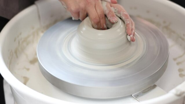 Female potter works with potter weel, craftsman hands close up. Hands of potter making clay pot. High quality 4k footage