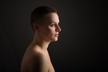 portrait of young woman with short hair and bare shoulder on black background