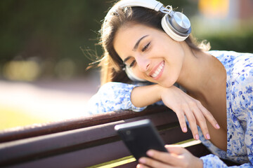 Happy female listening to music in a bench