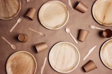Flat lay composition with eco-friendly tableware on brown paper background. Bamboo plates, paper...