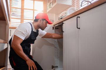 A plumber is repairing and fixing the water system in a customer's house. In-house service and...
