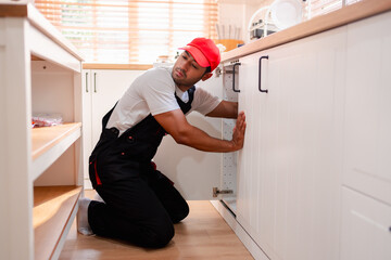 A plumber is repairing and fixing the water system in a customer's house. In-house service and troubleshooting.