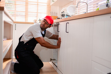 A plumber is repairing and fixing the water system in a customer's house. In-house service and...