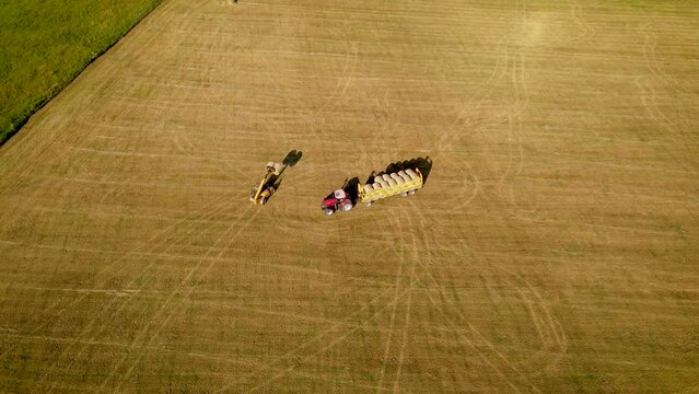 Telehandler loading bales onto truck, taking hay round bales from field. Agricultural machinery. Work in agronomic farm for making business and production organic eco bio animal feed