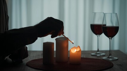 Romantic evening by candlelight. Hands of a man lighting candles with matches close up. Burning...