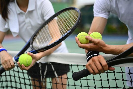 Experienced male tennis coach giving instructions to his student, standing by net at the outdoor tennis court - Powered by Adobe