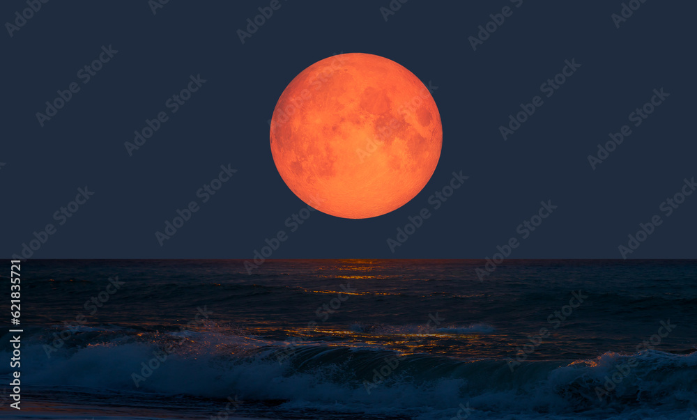 Wall mural night sky with orange moon in the clouds over the calm blue sea 