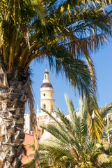 st michael basilica campanile in Menton city, framed with palm trees