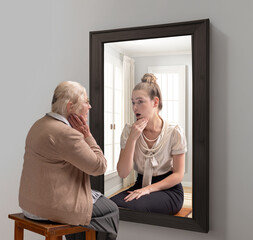 Creative conceptual collage. Senior woman looking in mirror and remembering her past. Young girl in reflection. Aging. Concept of present, past and future, age, lifestyle, memories, generation, ad