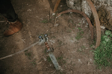 Roman sword embedded in the earth, secured with a rope, placed near a sturdy stone wall, evoking...
