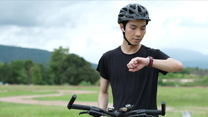Sports man biker using GPS activity tracker fitness watch at training in the park sports man using...