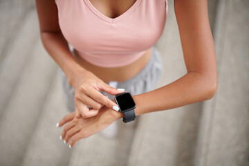 Fit woman checking heartbeat via app on smartwatch after morning run
