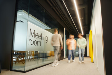 motion blur of energetic and ambitious business people walking near meeting room in coworking...