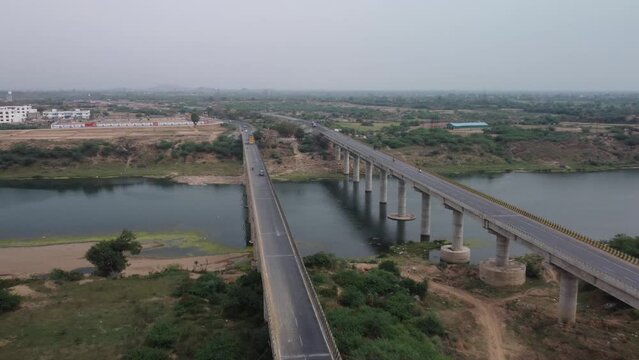 Highway bridge built over the river basin in the rural terrain, India, Aerial view, Slow motion