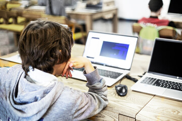 tenager boy writes codes on a computer at school in a programming lesson. Back to school. Modern IT...