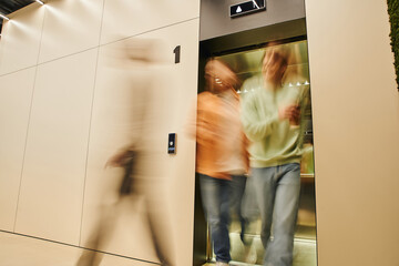 motion blur of energetic businessmen getting out elevator in contemporary coworking office, long exposure, movement, collaboration, dynamic business and productivity concept - obrazy, fototapety, plakaty