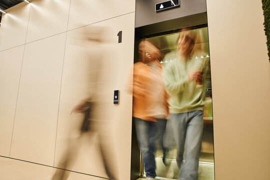 motion blur of energetic businessmen getting out elevator in contemporary coworking office, long exposure, movement, collaboration, dynamic business and productivity concept