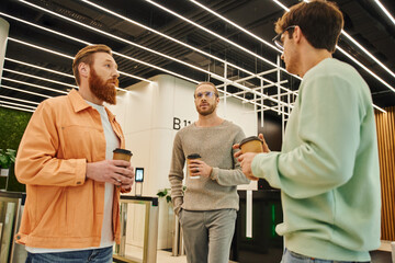 Obraz premium thoughtful entrepreneurs in stylish casual clothes holding paper cups with takeaway drinks during discussion in lobby of modern coworking office, businessmen solving problem during coffee break