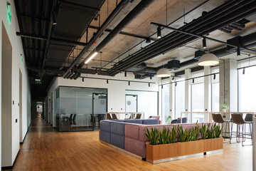 spacious and contemporary office lounge with soft and comfortable couch, large windows, high chairs and green plants, workspace organization concept - Powered by Adobe