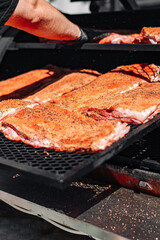 Chef hand cooking grilled pork meat in BBQ smoker.