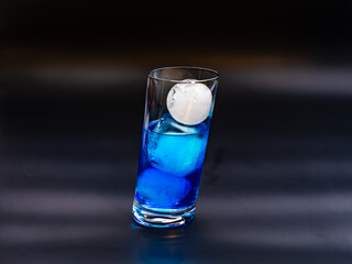 Long drink with ice in a glass isolated against black
