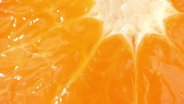 The lens delves into the microscopic realm, uncovering the finer aspects of the orange slice. Microdroplets of juice adorn the surface of the pulp, sparkling like tiny diamonds. Orange background
