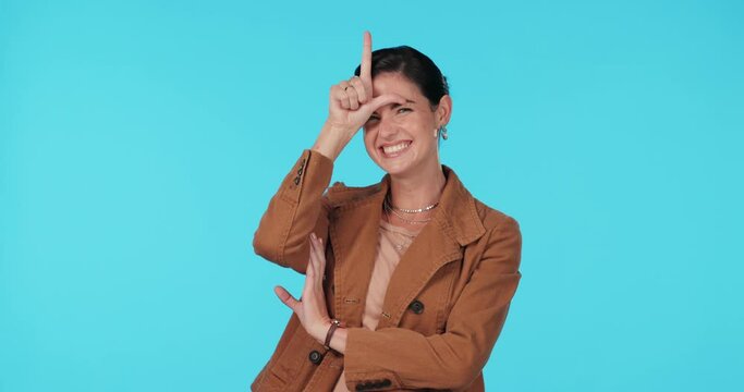 Business woman, loser sign and laughing in studio for mocking, winning or fun humour. Portrait of female model show emoji on forehead for competition, funny face or gesture on a blue background