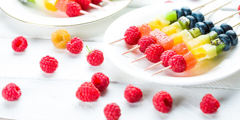 Kebab with raspberries, kiwi, orange and other fruits on the plate