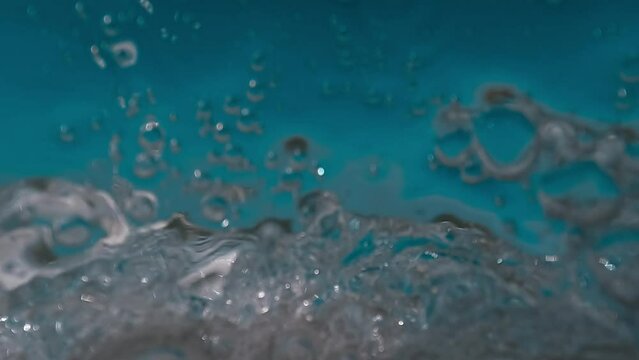 Half underwater first person view of sea waves splashing on camera. Slow-motion