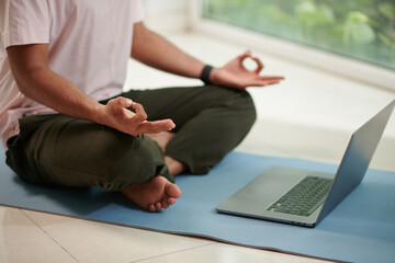 Fototapeta premium Man following tutorial on laptop when learning how to meditate