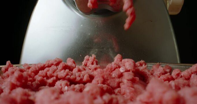 Fresh minced meat in glass bowl meat grinder is working camera is moving up and down. Slow motion black background. Cook food Advertising. Making minced meat in a meat grinder electric machine