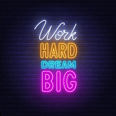 Fototapeta na wymiar Work Hard Dream Big neon lettering on brick wall background.