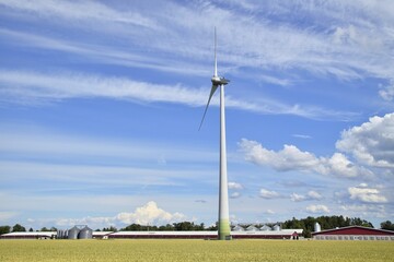 Obraz premium Wind turbine against the sky with clouds near the farm.