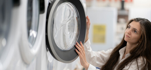 young woman in the store choosing the washing machine