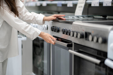 woman buying a new kitchen stove in the electronics retail store - obrazy, fototapety, plakaty