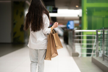 woman walking in the shopping mall and carry the paper bags with new purchases