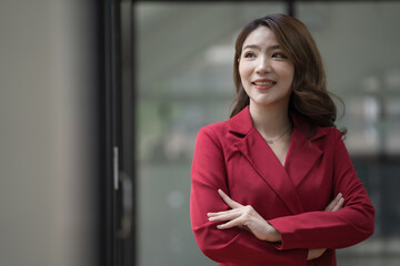 Confident Asian businesswoman standing with crossed arms and looking away.