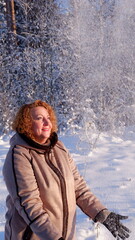 Girl with red hair in winter snow on a sunny day