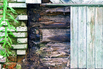 Rotten logs under the exterior lining of a wooden house