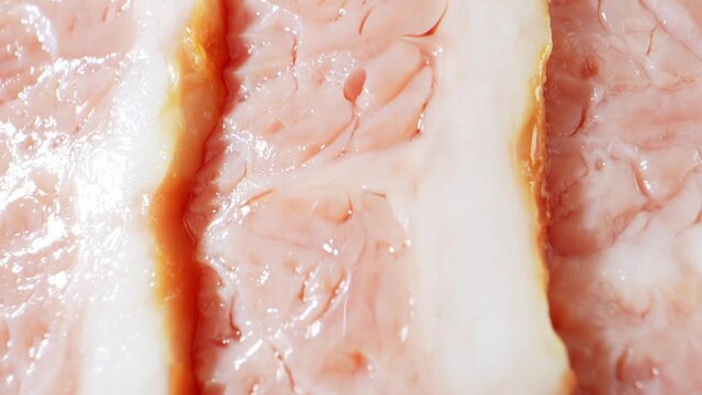 A mesmerizing macro video showcases raw bacon up close, capturing its marbled texture, glistening fat, and rich red hues with stunning detail. Processed food concept. Bacon background. 4K HDR
