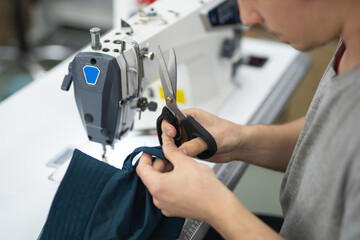 workers in an industrial garment factory sew clothes on sewing machine