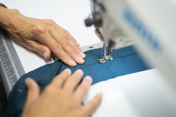workers in an industrial garment factory sew clothes on sewing machine