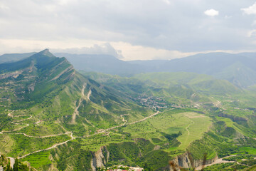 The landscape of the Caucasus Mountains on the background of a blue sky with clouds.