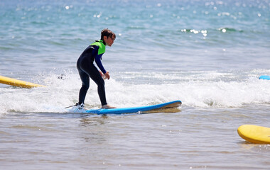 Child on a surfboard on the beach, in summer, on vacation