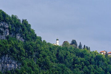 Scenic landscape with rock, cliff and woodland with mountain village Seelisberg and church at lakeshore of Lake Uri on a cloudy spring day. Photo taken May 18th, 2023, Seelisberg, Switzerland.